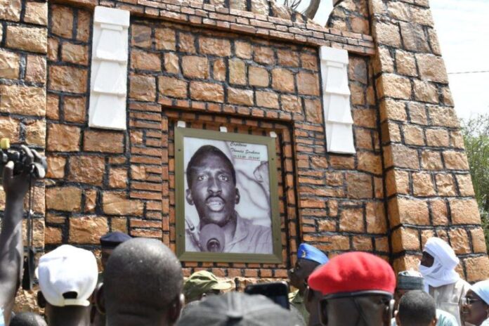 A military official in green uniform wearing a blue cap, unveiling the new plaque reading Avenue Djibo Bakary