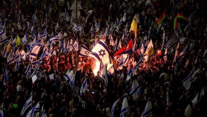 A person holds an Israeli flag as people demonstrate after Israeli Prime Minister Benjamin Netanyahu sacked his defense minister, Yoav Gallant, citing lack of trust, in Tel Aviv, Israel November 5, 2024.